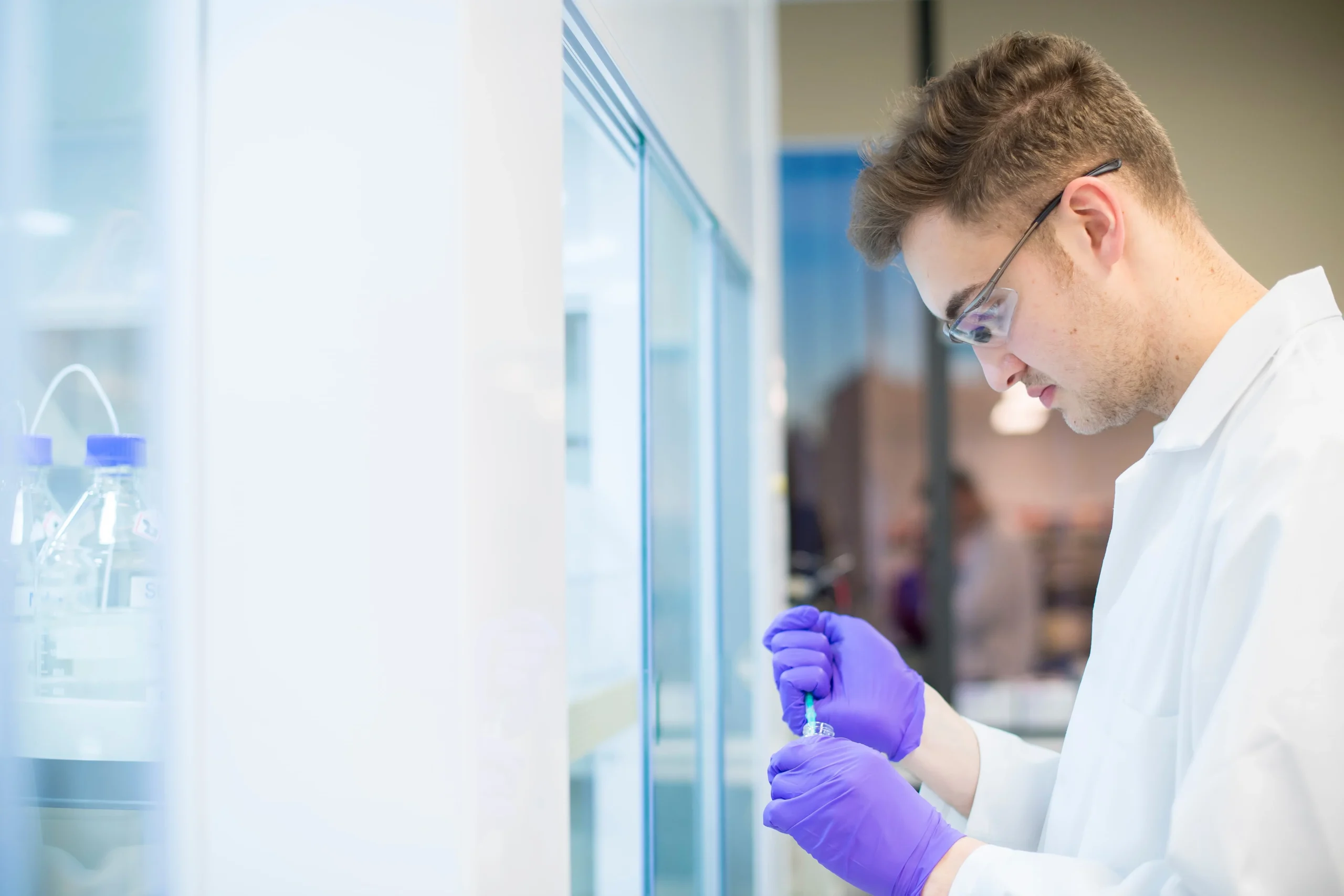 Laboratory setup with a researcher working near advanced equipment, illustrating assay development for drug discovery workflows.
