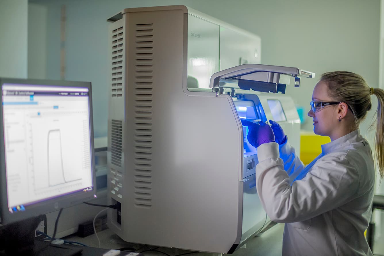 Scientist operating specialized biophysical assay equipment to study molecular interactions and protein stability.