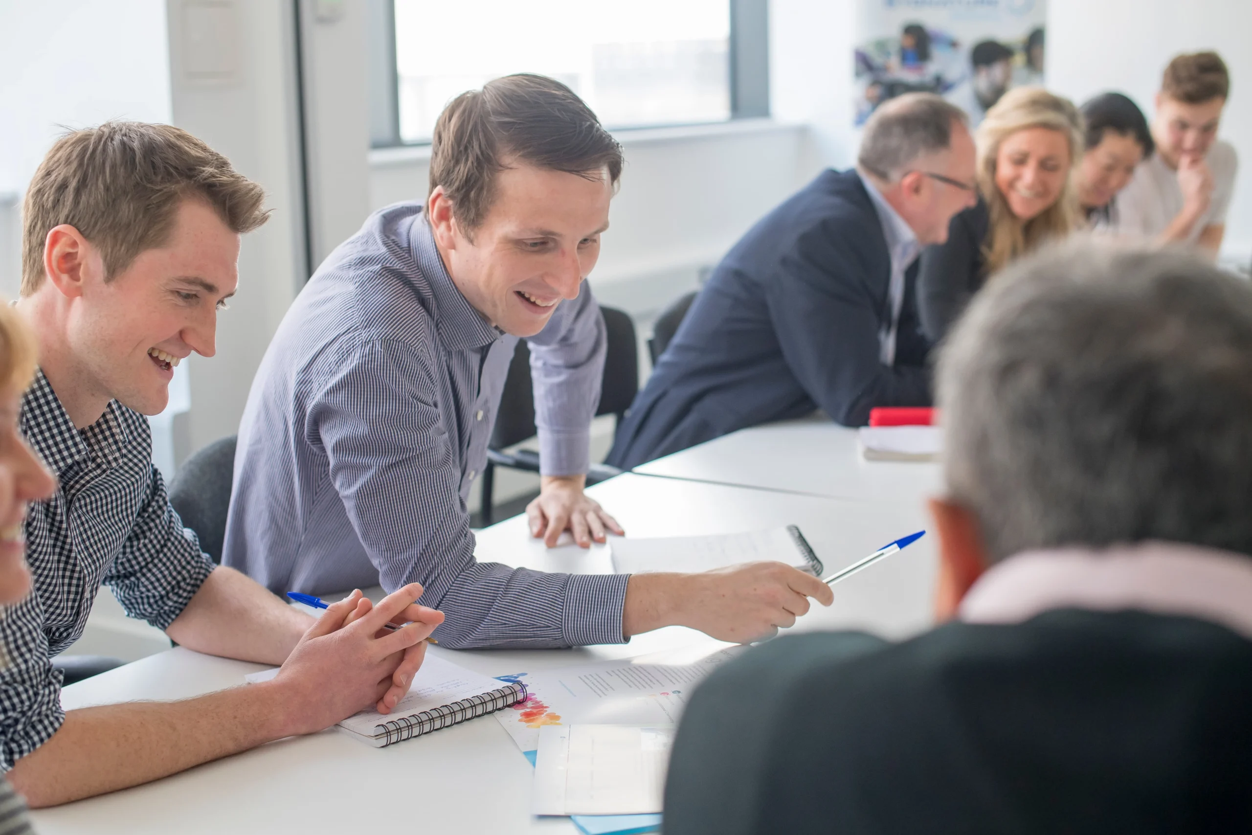 Group of professionals seated around a meeting table engaged in discussion, representing independent DMPK review and strategic problem-solving to strengthen drug discovery programs.