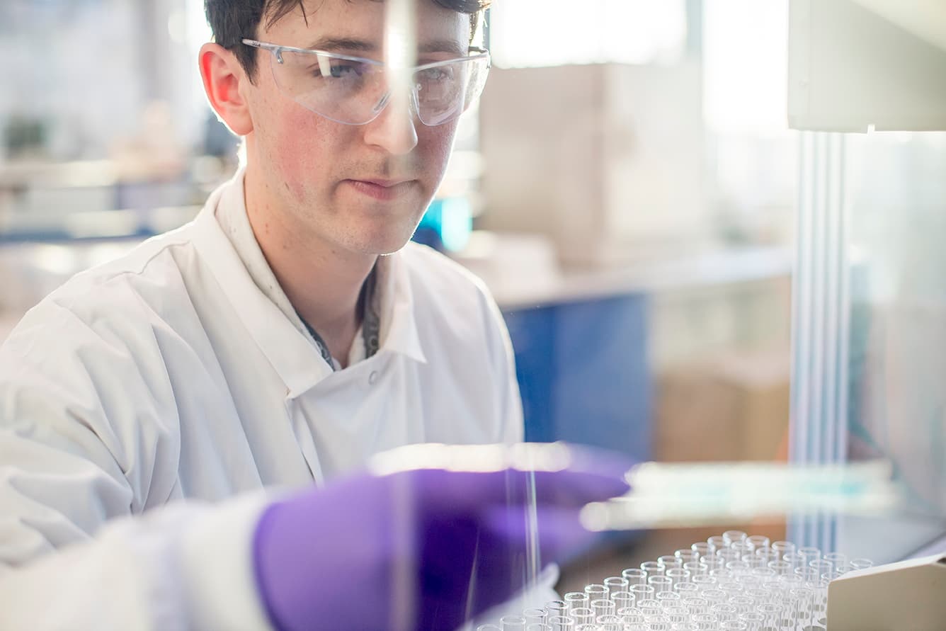 Gloved hand handling laboratory samples in a controlled environment, representing primary cells and tissue preparation for research and drug discovery.