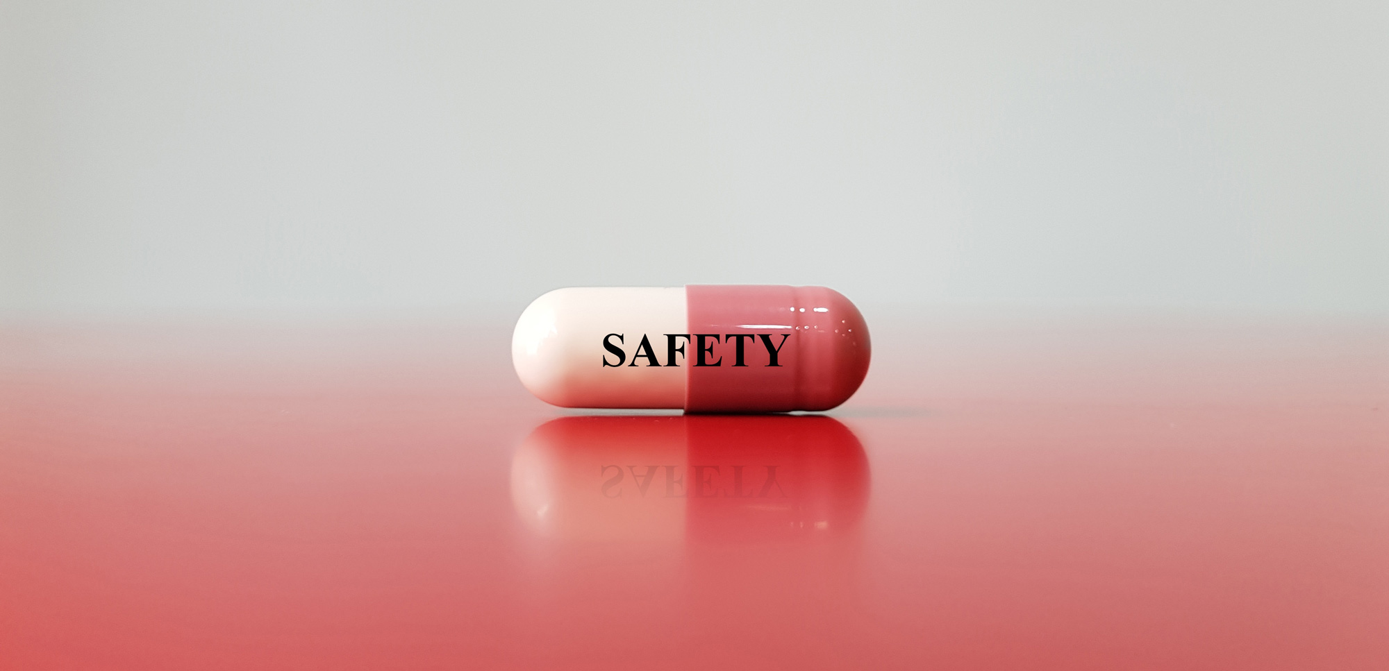 Gros plan sur une capsule étiquetée « SÉCURITÉ » sur une surface rouge, symbolisant l'évaluation précoce de la sécurité et de la tolérance dans le développement des médicaments afin de guider une prise de décision éclairée.