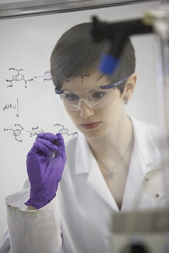 Laboratory setting with chemical structures on a transparent board, representing small molecule drug discovery and synthesis for therapeutic development.